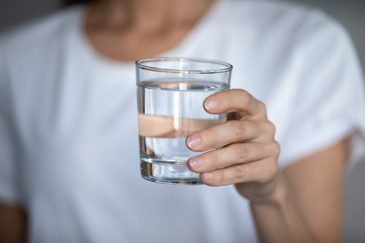 Young woman hold glass drinking pure mineral water